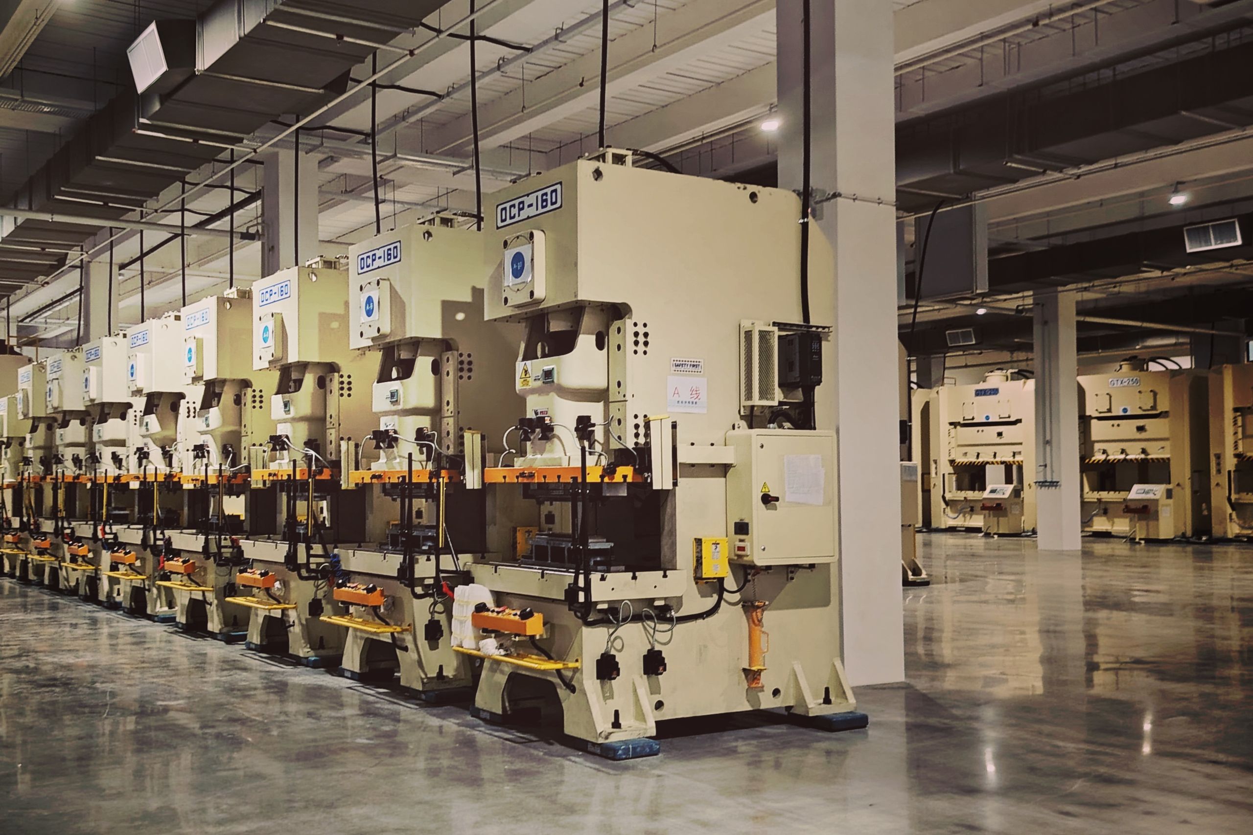 Üretim durmuşken makinelerin boşta beklediği, aydınlatması açık boş fabrika salonu — mesai dışı tüketim